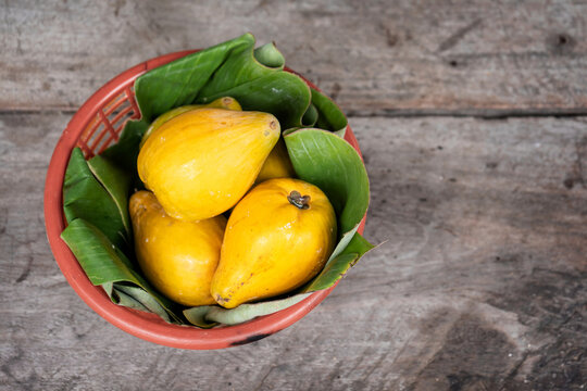 Yellow fruits are named Canistel, Egg fruit, Tiesa, Yellow sapote, Canistelsapote, Chesa(Philippines), Laulu lavulu or Lawalu (Sri Lanka) on the old rustic wooden table.