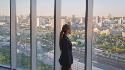 Woman leader thinking future looking panoramic window in contemporary office.
