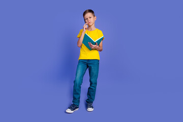Fototapeta na wymiar Photo of minded cute boy wear trendy yellow clothes hold book textbook solve question isolated on violet color background