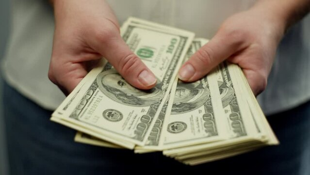 A woman counts a stack of hundred-dollar bills in her hands. Cash settlement in business. High quality 4k footage