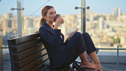 Calm worker sipping coffee resting morning terrace. Peaceful woman check mobile - obrazy, fototapety, plakaty
