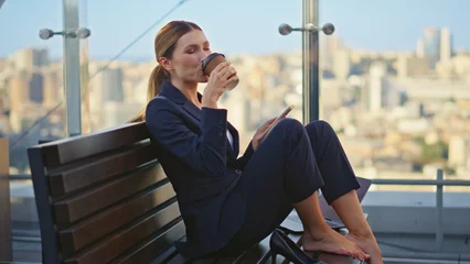 Fotobehang Calm worker sipping coffee resting morning terrace. Peaceful woman check mobile © stockbusters