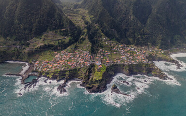 Aerial view of Seixal, a little village by the ocean with waves and surrounded with incredible mountains on the island of Madeira, Portugal.