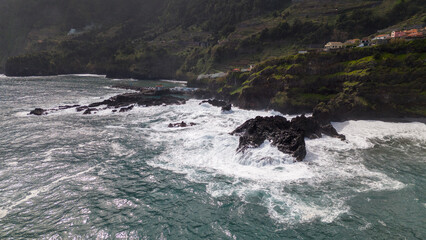Aerial view of Seixal, a little village by the ocean with waves and surrounded with incredible mountains on the island of Madeira, Portugal.