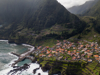 Fototapeta na wymiar Aerial view of Seixal, a little village by the ocean with waves and surrounded with incredible mountains on the island of Madeira, Portugal.