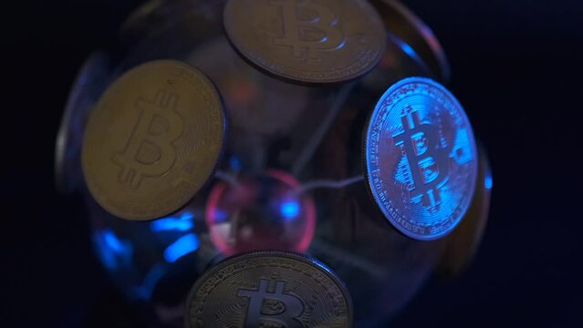 Rotating plasma sphere with golden bitcoins alarmingly flashing blue and red neon light jerking close-up on black background.