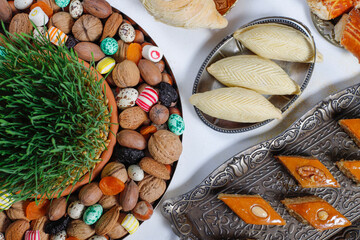 Traditional Azerbaijan holiday Novruz background with green semeni,traditional azerbaijan sweets,shekerbura,qogal,paxlava,mutaki and different nuts and sweets,top view,space for copy