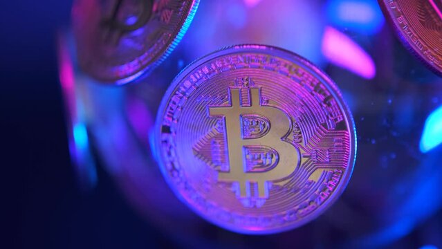Close up bitcoin BTC in purple neon light slow motion macro close up, digital coins abstract cyberpunk background. Concept of wealth and investment.