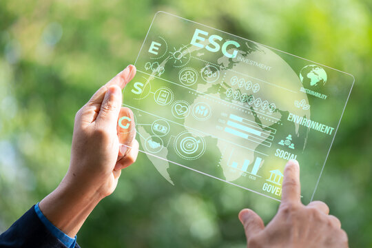 Hand holding and showing transparent tablet device. Business, natural green bokeh background,technology concept,alternative energy,conservative clean energy,ESG concept,Carbon credit,Carbon neutral.