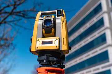 land surveying total station instrument on a tripod with a building in the background