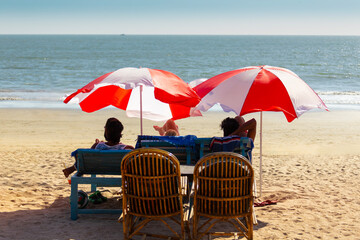 Vacationers under colorful umbrellas on the ocean shore - 764096509