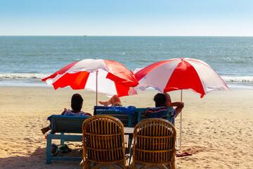 Vacationers under colorful umbrellas on the ocean shore - 764096545