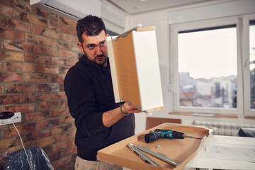 Man working and assembling furniture in a new apartment.