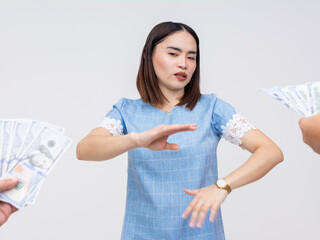 A determined Asian woman in a blue dress makes a no gesture to refuse accepting money as a bribe...