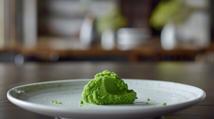 A small mound of vibrant green wasabi paste sits on a white porcelain plate, ready to be used as a condiment