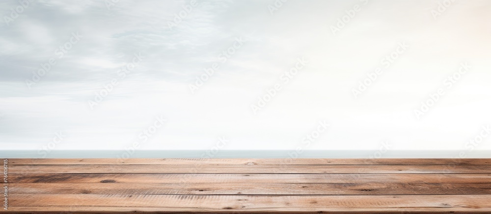 Wall mural A wooden table top with a serene view of the expansive ocean and clear blue sky