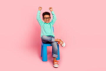 Full size photo of charming small boy sit chair raise fists specs dressed stylish cyan outfit...