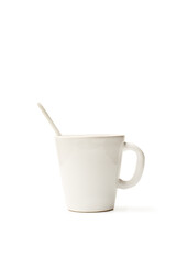 Una taza blanca de cerámica con una cuchara sobre un fondo blanco liso y aislado. Vista de frente y de cerca. Copy space. Formato vertical - 764107784