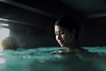 Woman gazing thoughtfully through a glass surface