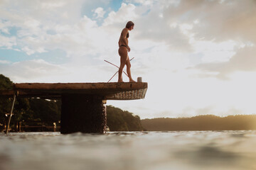 Person standing on a dock over water at sunset