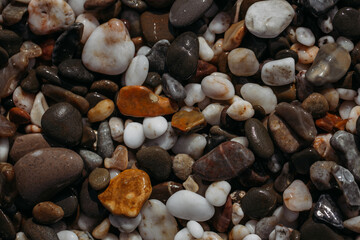 Sea stones of different colors on the shore in close-up
