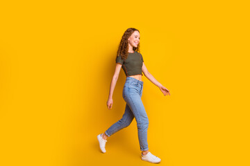 Fototapeta na wymiar Full length photo of cheerful lovely cute girl wear trendy outfit go store mall center empty space isolated on yellow color background