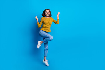 Fototapeta na wymiar Full length photo of positive lucky woman wear shirt jumping high rising fists empty space isolated blue color background