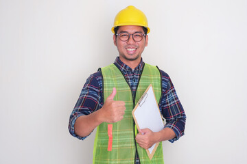 A construction worker smiling and give thumb up while holding checklist on clipboard
