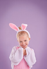 Portrait, rabbit and girl with costume, happiness and Halloween outfit on a purple studio background. Face, kid and model with bunny clothes and character with smile and Easter holiday with culture