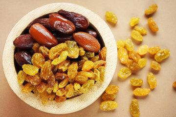 Dried dates and raisins in a wooden plate on a light background