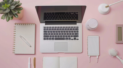 A neatly organized desk with a laptop, smartphone, notebook, and accessories on a pink surface.