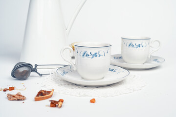 Still life with fine porcelain tea cups and accessories on a textured white background - 764139500