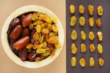 Dried dates and raisins in a wooden plate on a beige-brown background