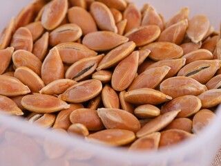 A close-up shot of pumpkin seeds in a plastic container.