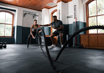 Man and woman play with ropes on gym flooring near a window - obrazy, fototapety, plakaty