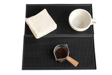 Measuring cup with wooden handle on bar mat over white background.