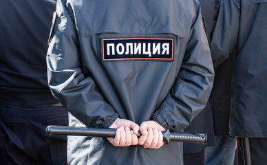 Russian policeman in the uniform with inscription Police and with truncheon
