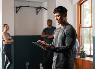 A man is using a tablet computer in the gym, gesturing near the window