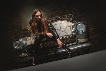 Young beautiful girl sits on the metal sofa car. Beauty and fashion.