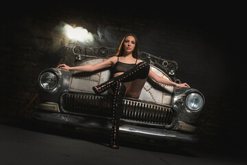 Young beautiful girl sits on the metal sofa car. Beauty and fashion.