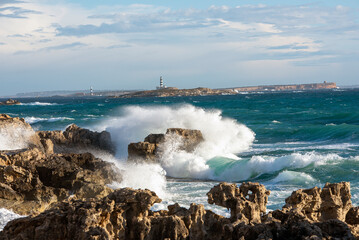 View of the wavy coastline with En Pou lighthouse in Des Porcs Island in the background, Las Salinas Natural Park, Ibiza Island, Balearic Islands, Spain