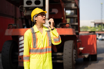 Asia logistic engineer man worker or foreman working with walkie talkie at container site	