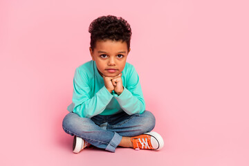 Full body photo of cute little boy sit floor think charming look camera dressed stylish cyan clothes isolated on pink color background