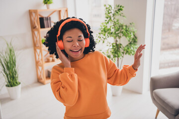 Photo portrait of lovely young lady headphones dancing dressed casual orange clothes cozy day light home interior living room