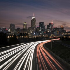 A photo of a lit up city skyline with a light trails from a traffic time lapse.