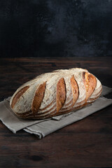 Sourdough bread. Freshly baked organic wheat bread on a dark background,  with linen tablecloth. Copy space.