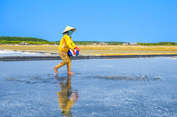 A woman is spreading salt to stimulate salt crystallization on her salt field in Can Gio district, a suburban district of Ho Chi Minh City, Vietnam.