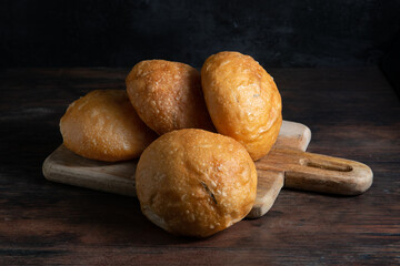 Baked buns. Freshly baked bread rolls on a cutting board. Black background