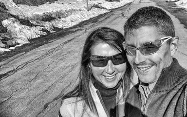 A happy caucasian couple taking selfies with a beautiful winter mountain scenario