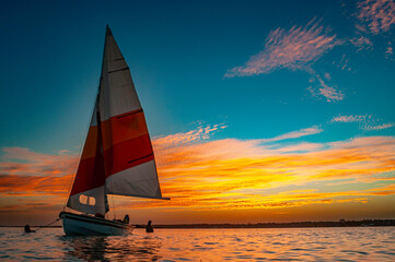 Laguna de Bacalar, barco, atardecer, agua cristalina, cielo naranja, reflejos, horizonte, serenidad, paisaje natural, destino turístico